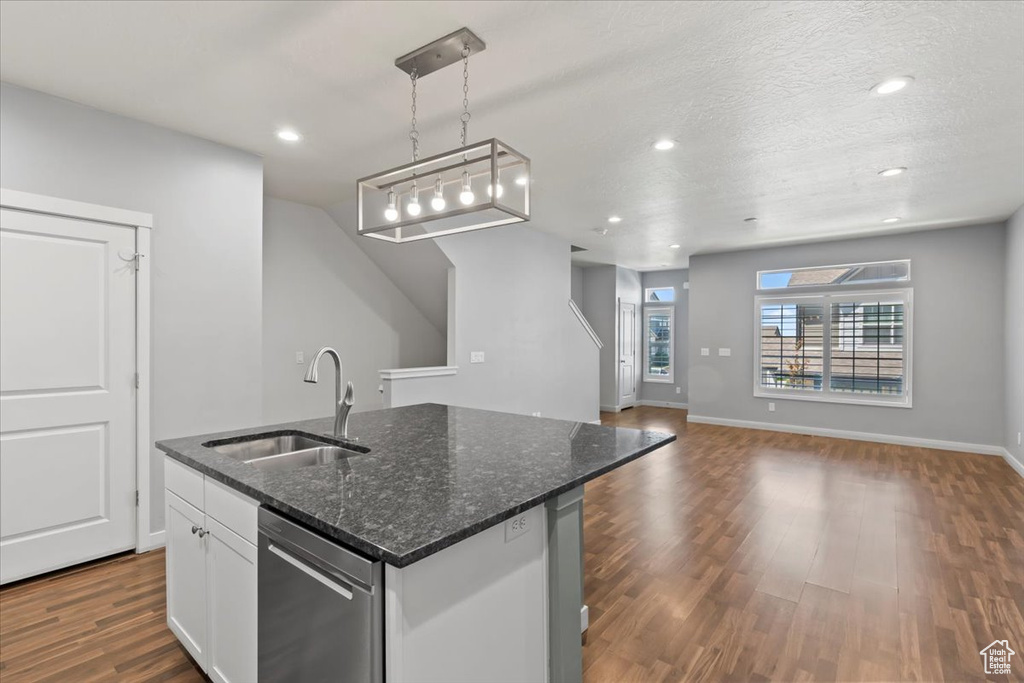 Kitchen with stainless steel dishwasher, dark wood-style flooring, white cabinetry, an island with sink, and recessed lighting