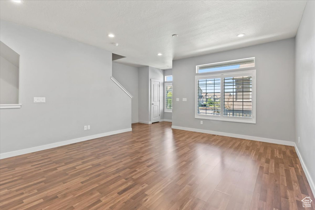 Unfurnished living room with wood finished floors, recessed lighting, and a textured ceiling