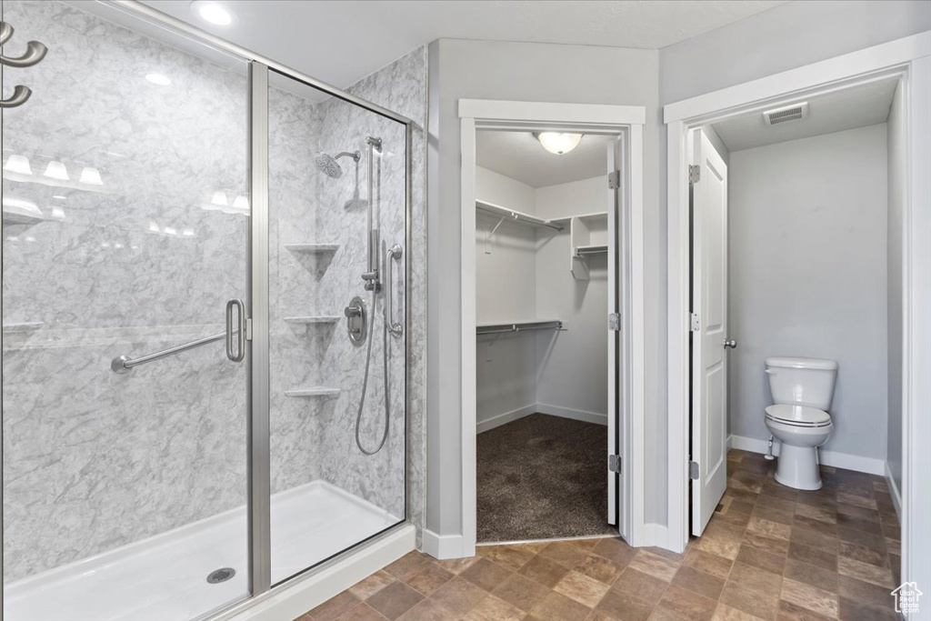 Full bathroom with a shower stall, a spacious closet, and stone finish floors