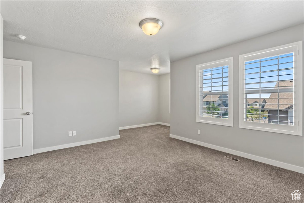 Carpeted spare room with a textured ceiling and a smoke detector