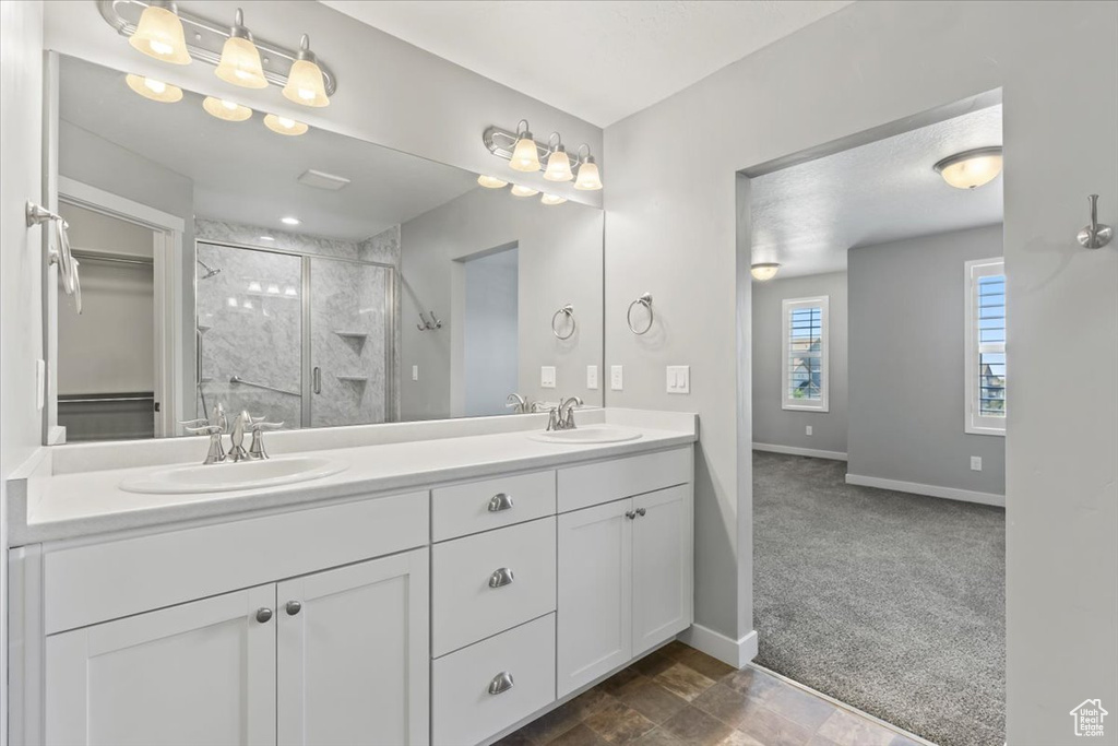 Full bath with a shower stall, double vanity, and a spacious closet