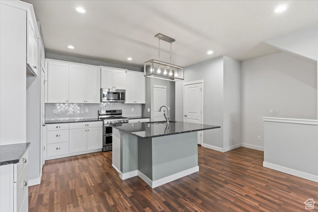 Kitchen featuring appliances with stainless steel finishes, dark wood-style floors, tasteful backsplash, white cabinetry, and recessed lighting