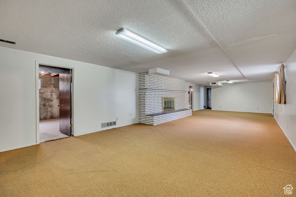 Unfurnished living room featuring carpet, a fireplace, and a textured ceiling