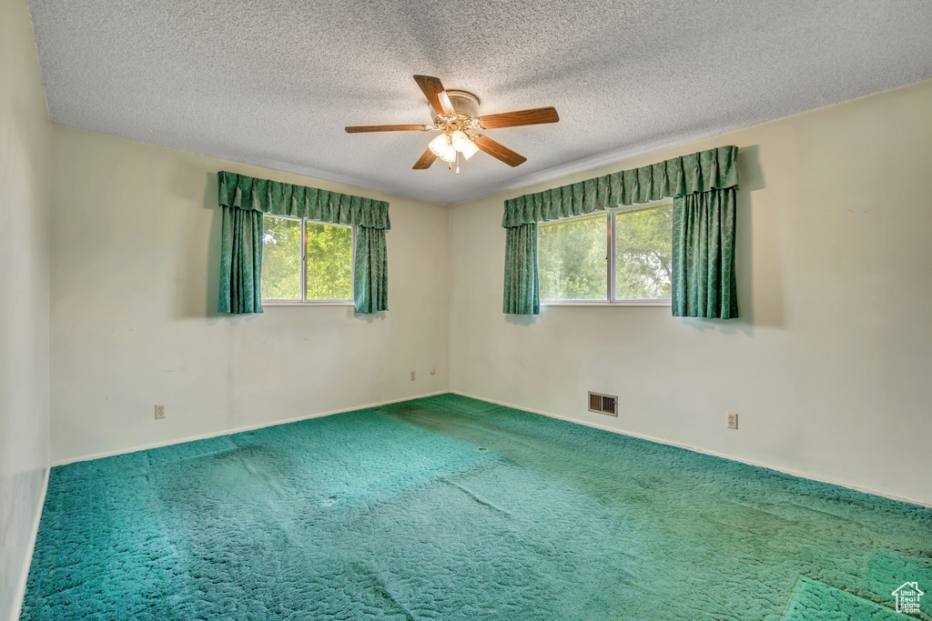 Carpeted spare room featuring ceiling fan and a textured ceiling