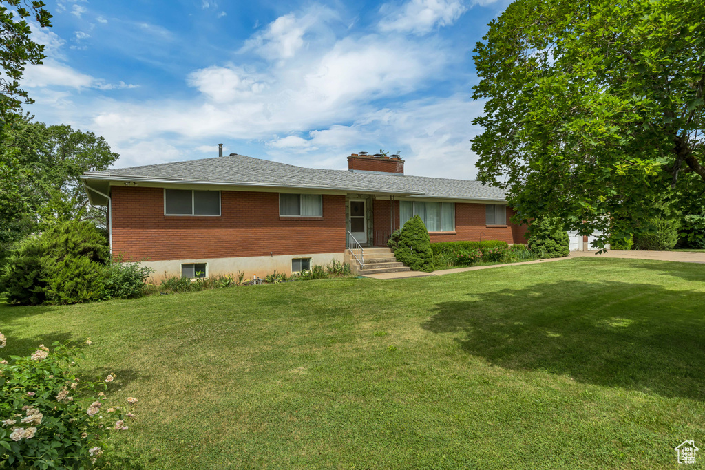 Single story home featuring brick siding, a front lawn, and a chimney