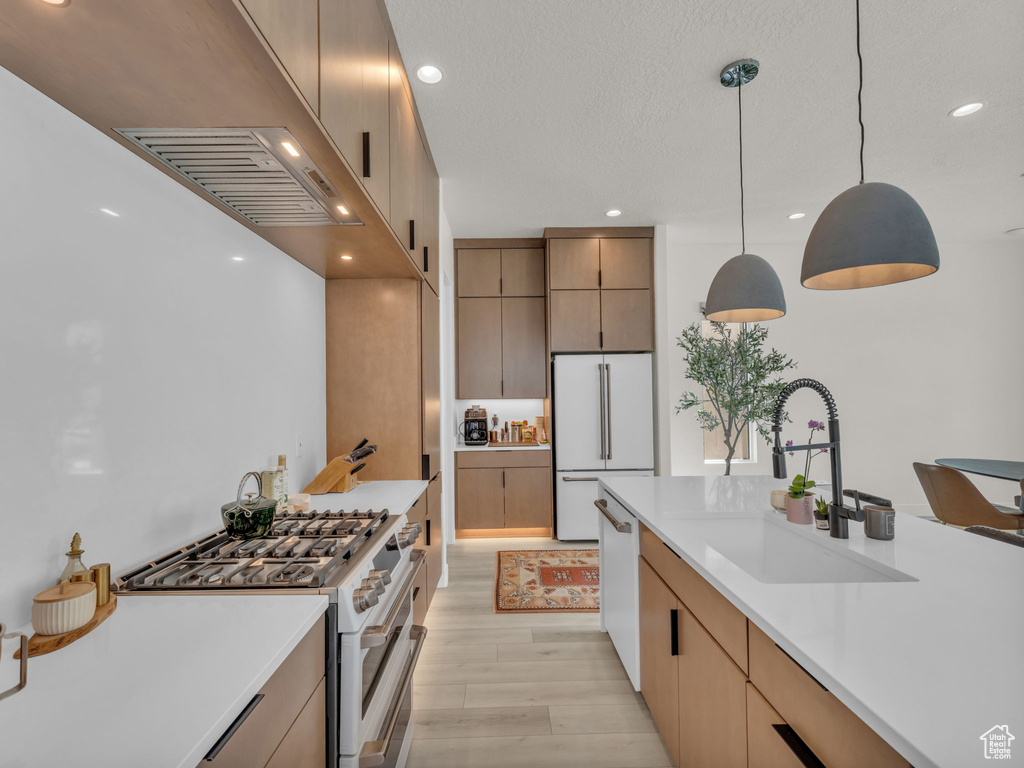 Kitchen featuring white appliances, light countertops, pendant lighting, light wood-style floors, and recessed lighting