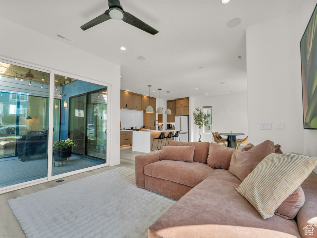 Living area with ceiling fan, light wood-type flooring, plenty of natural light, and recessed lighting