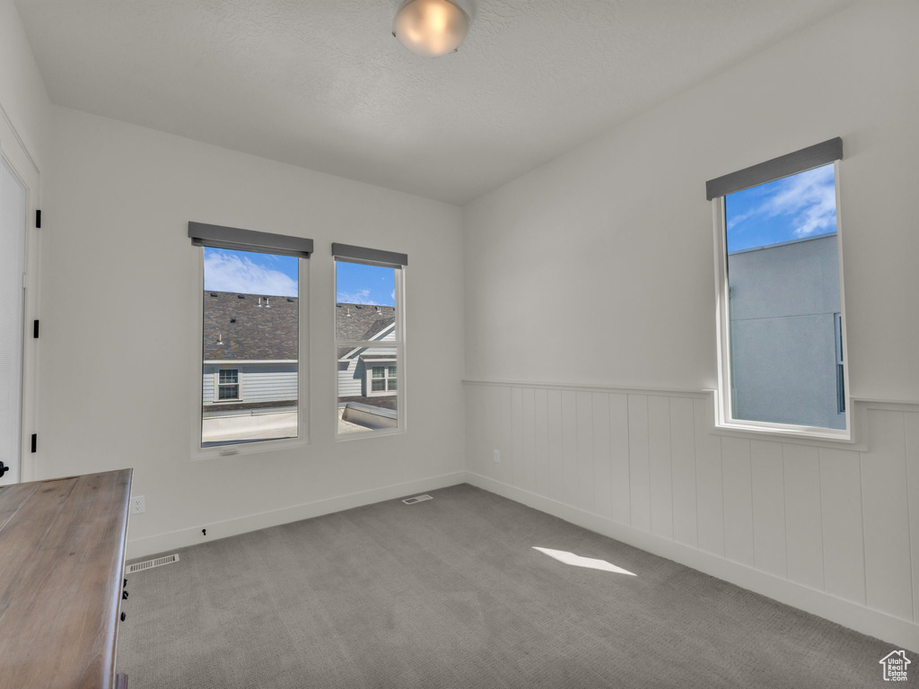 Unfurnished room featuring wainscoting and carpet