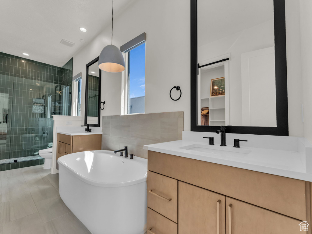 Bathroom with a stall shower, vanity, a freestanding tub, and tile patterned flooring