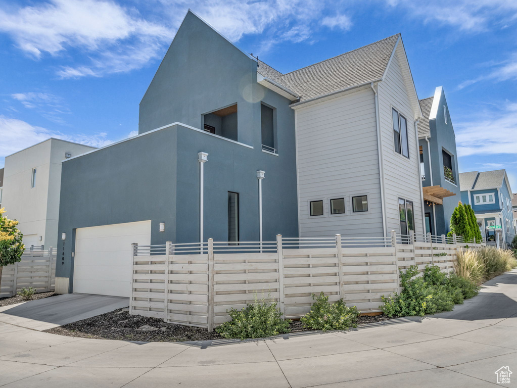View of side of property with a garage, driveway, a balcony, and stucco siding