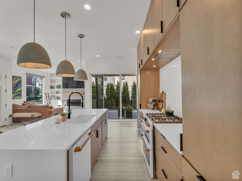 Kitchen featuring white appliances, modern cabinets, light countertops, recessed lighting, and light wood-type flooring