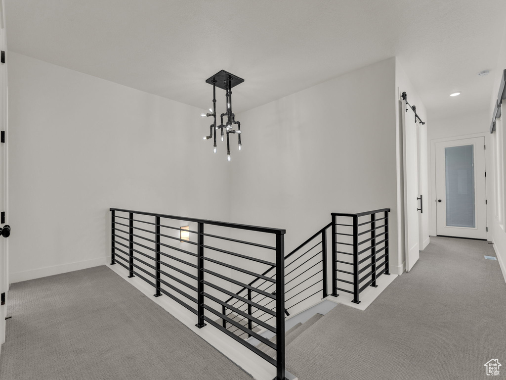 Hall featuring an upstairs landing, carpet flooring, a barn door, a chandelier, and recessed lighting