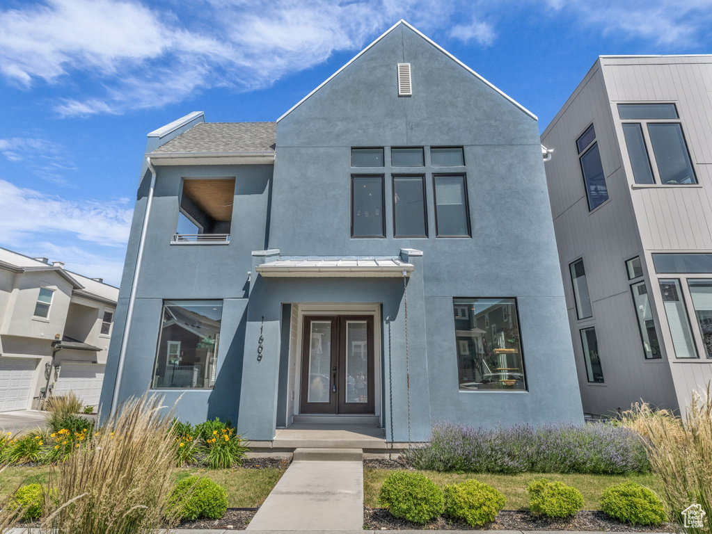 View of front facade with french doors, stucco siding, and a standing seam roof