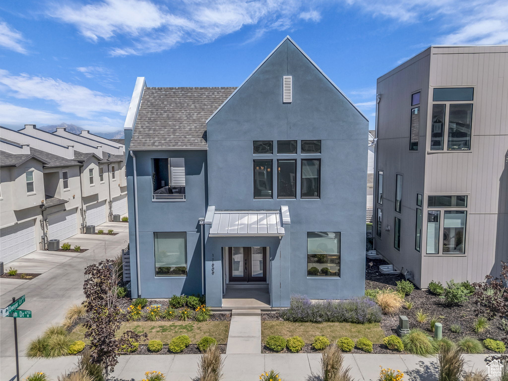 View of front of home featuring stucco siding, concrete driveway, a shingled roof, and a balcony
