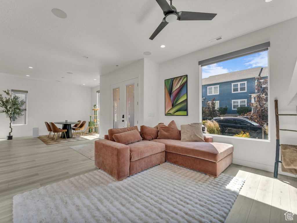 Living area featuring light wood finished floors, a ceiling fan, recessed lighting, and french doors