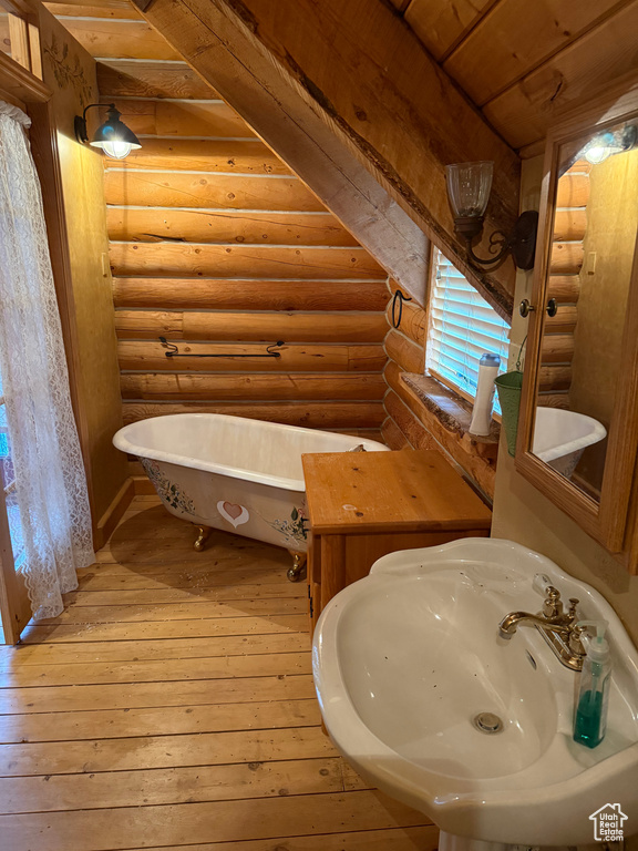 Full bath with rustic walls, a soaking tub, hardwood / wood-style floors, and wooden ceiling