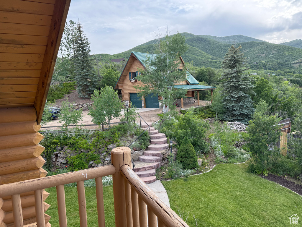 View of green lawn with a mountain view, a detached garage, and stairs