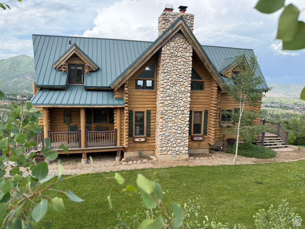 Back of house featuring a standing seam roof, a chimney, log exterior, a metal roof, and a mountain view
