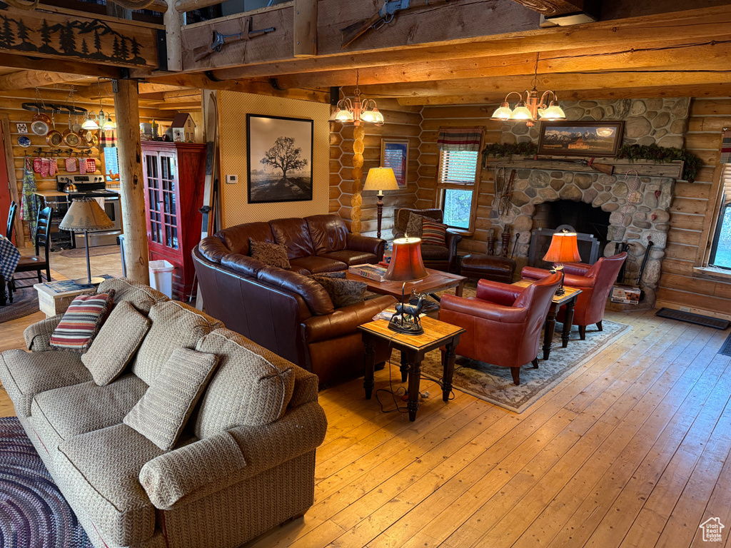 Living room with rustic walls, a chandelier, hardwood / wood-style flooring, healthy amount of natural light, and a fireplace