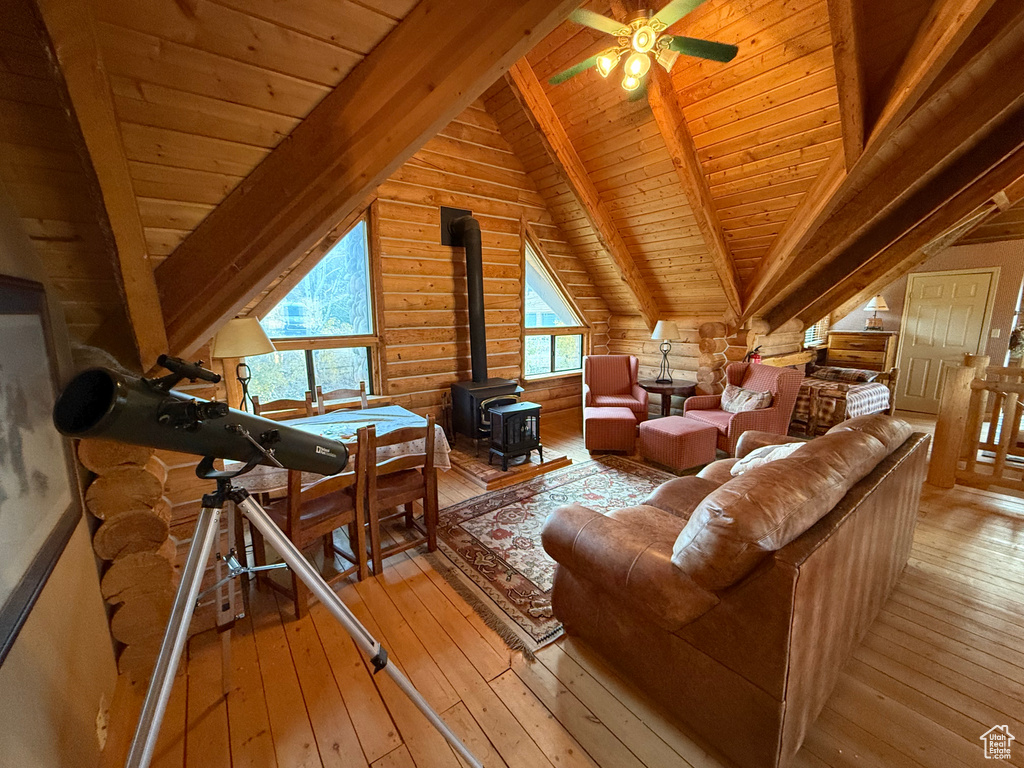 Living room featuring a wood stove, wood ceiling, light wood-style flooring, and ceiling fan