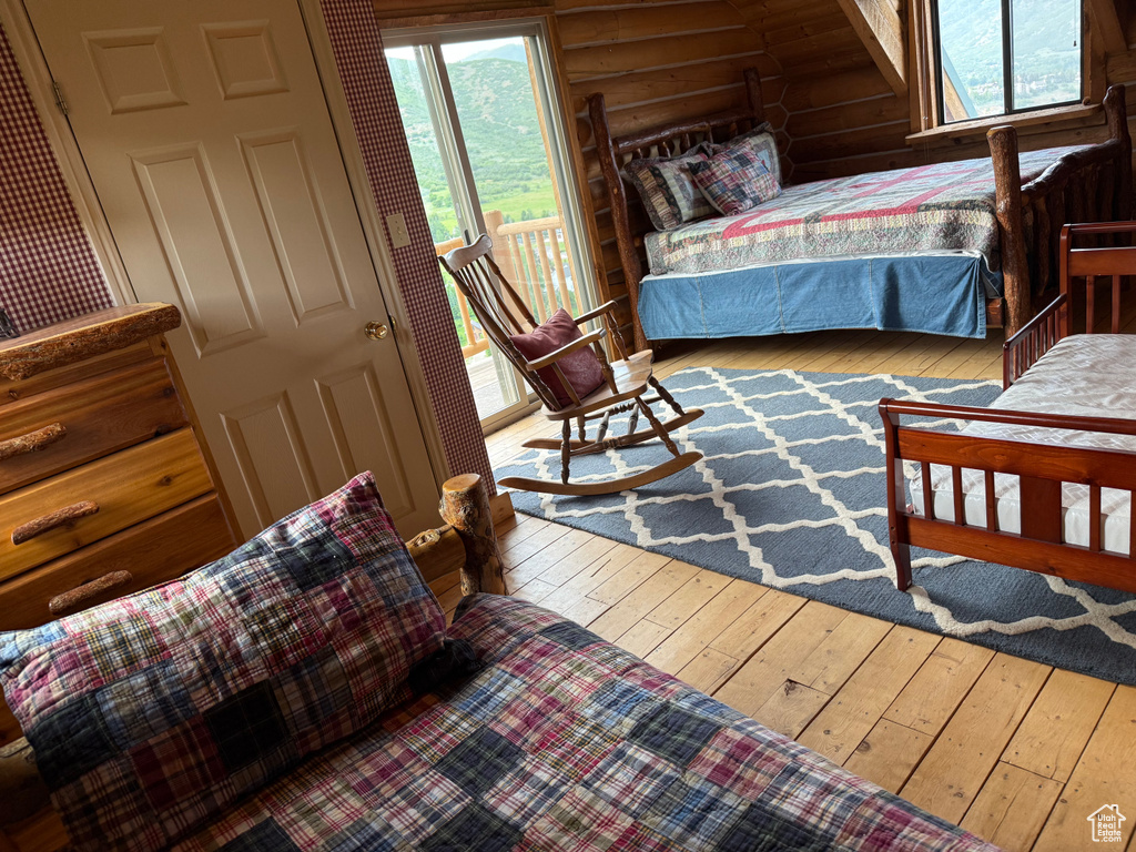 Bedroom featuring rustic walls, multiple windows, and hardwood / wood-style floors