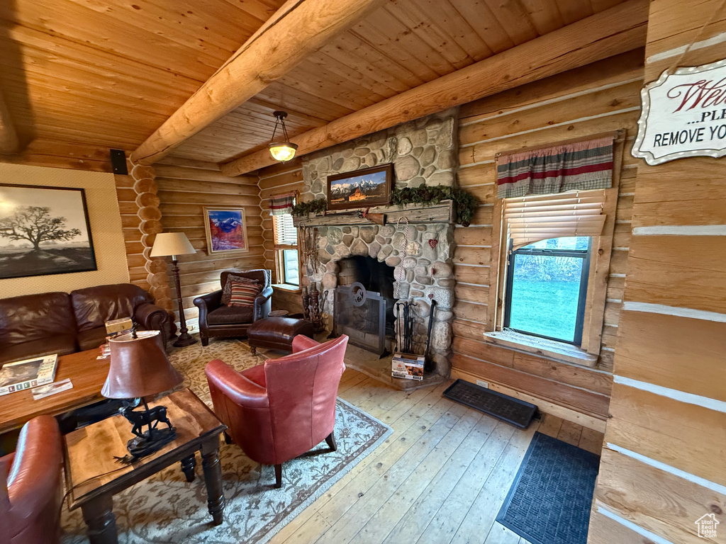 Living area featuring rustic walls, a wooden ceiling with exposed beams, hardwood / wood-style flooring, and a fireplace