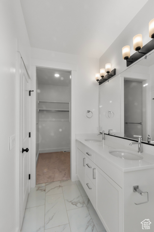 Bathroom with double vanity, marble finish floors, and a spacious closet