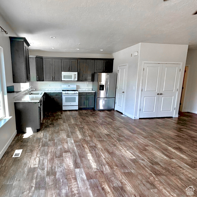 Kitchen featuring white appliances, dark wood finished floors, light countertops, tasteful backsplash, and a textured ceiling
