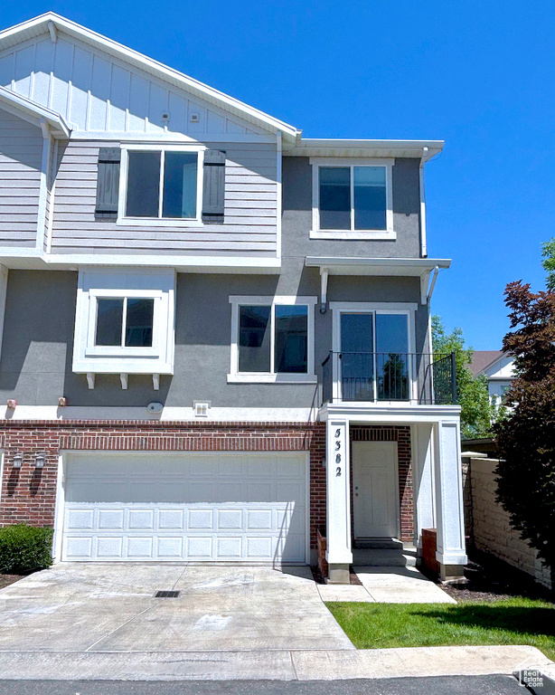 View of front of house featuring brick siding, stucco siding, and driveway