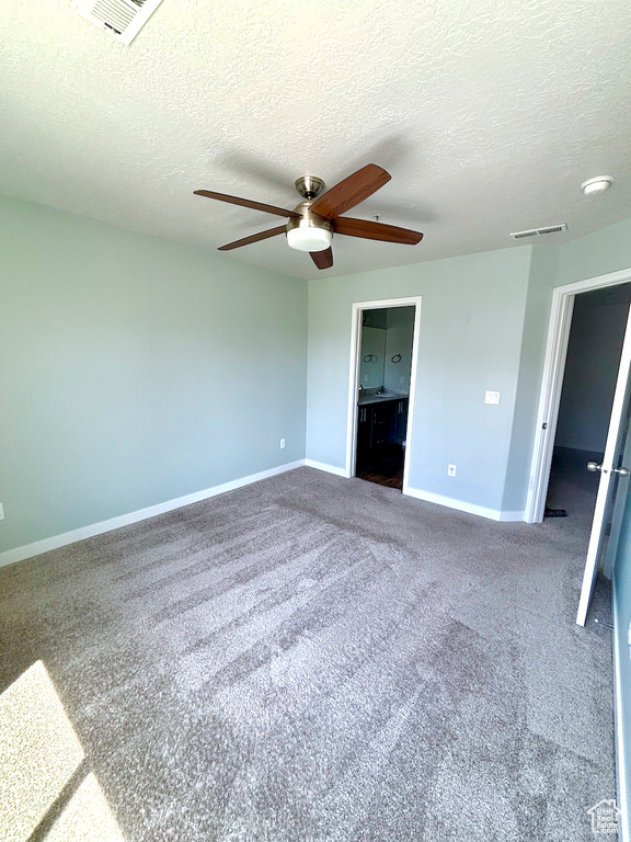 Unfurnished bedroom featuring carpet flooring, a textured ceiling, a ceiling fan, and ensuite bathroom