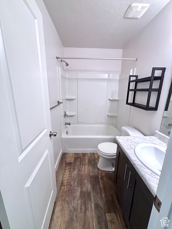 Full bathroom with vanity, wood finished floors, a textured ceiling, and shower / tub combination