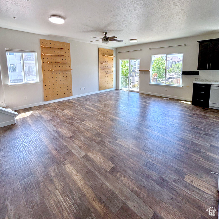 Unfurnished living room featuring dark wood finished floors, ceiling fan, and a textured ceiling