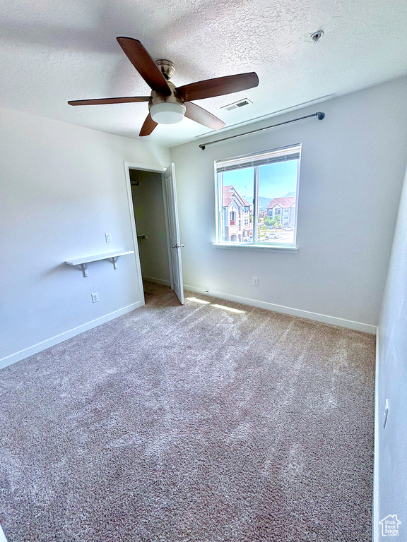 Unfurnished bedroom featuring a textured ceiling, carpet flooring, and ceiling fan
