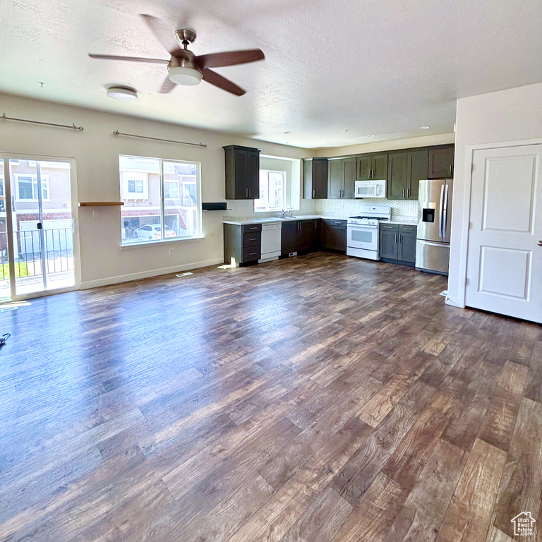 Kitchen featuring white appliances, dark wood-style floors, ceiling fan, light countertops, and a textured ceiling