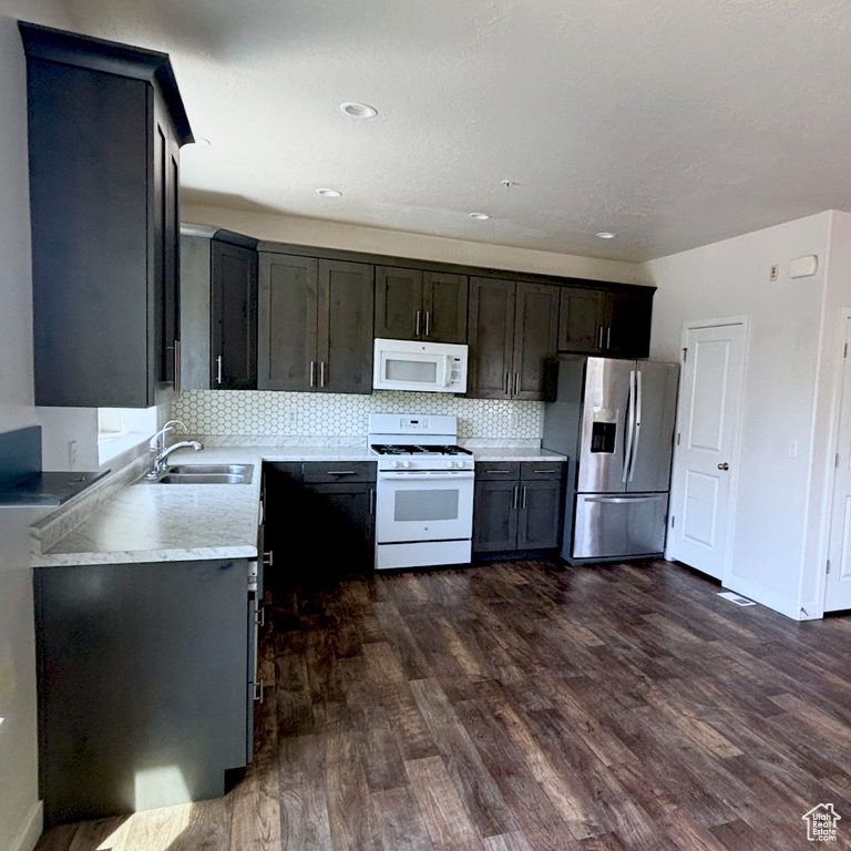 Kitchen featuring white appliances, dark wood finished floors, tasteful backsplash, and light countertops