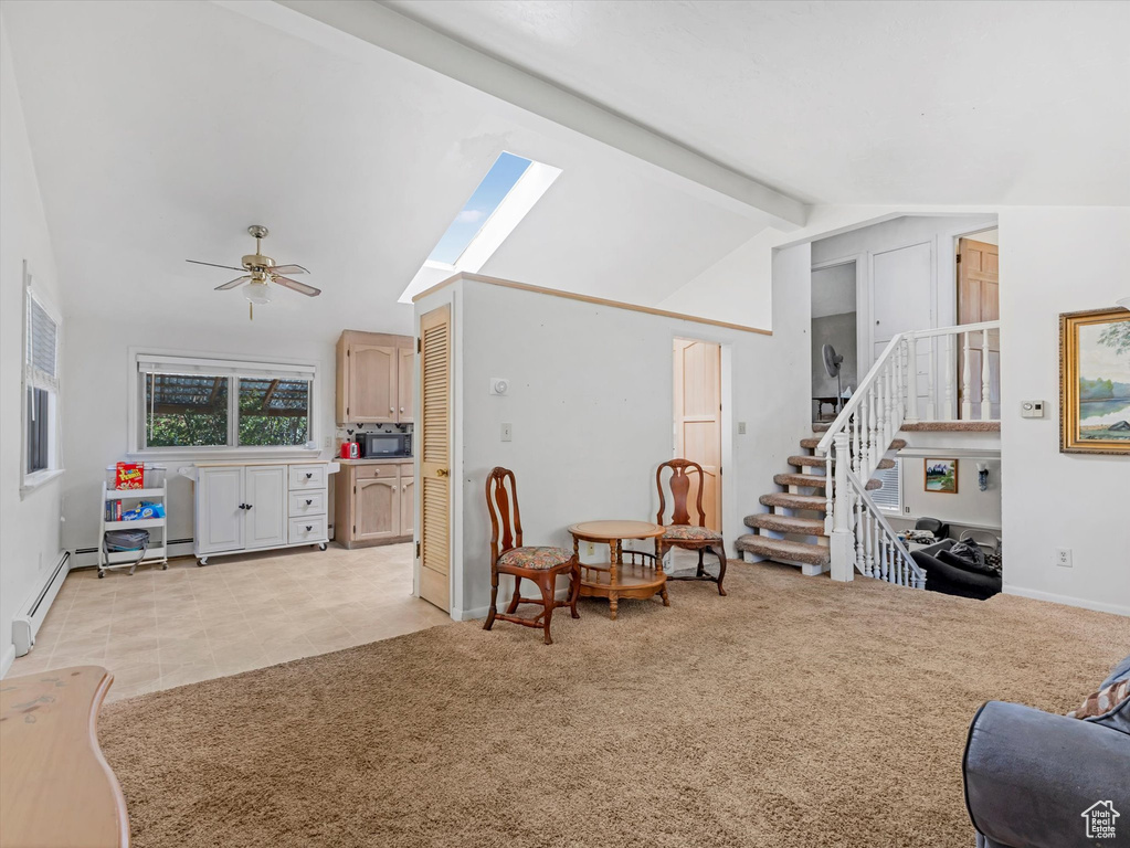 Living area with ceiling fan, a skylight, stairway, light carpet, and light tile patterned floors