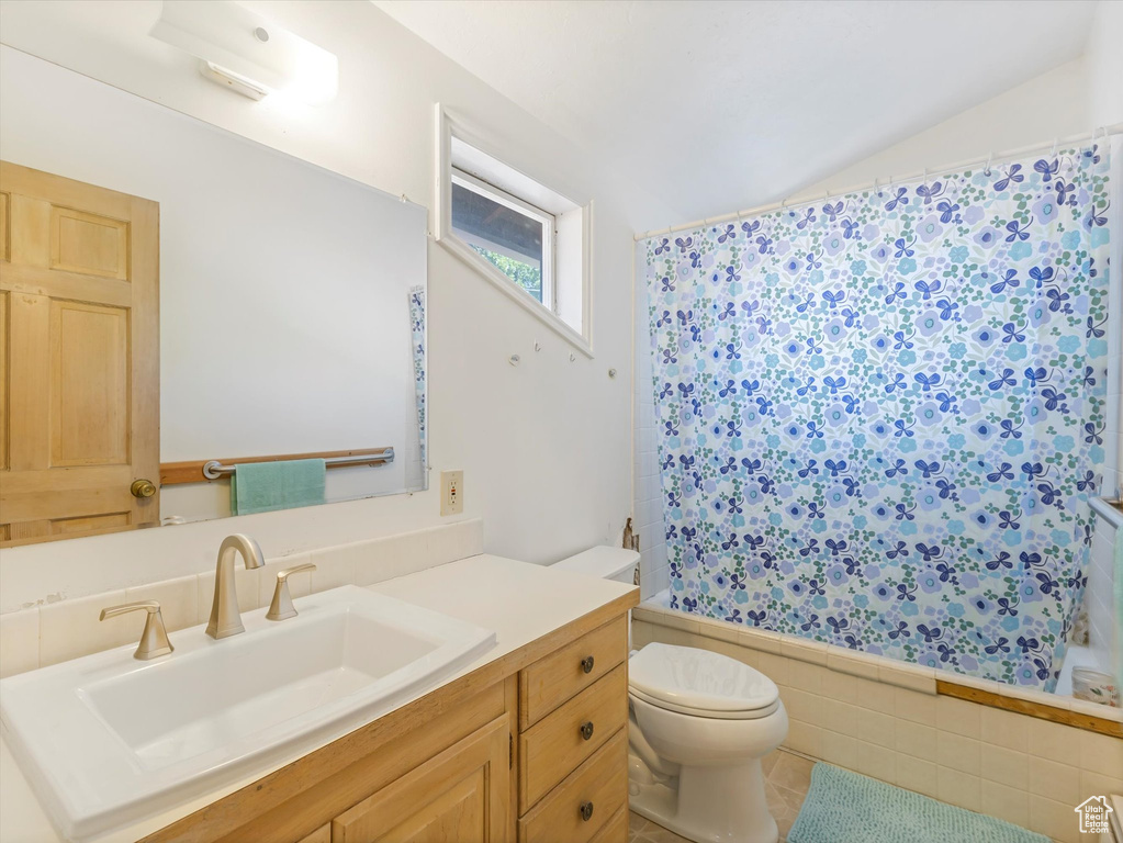 Bathroom with shower / bath combo with shower curtain, vanity, and tile patterned flooring