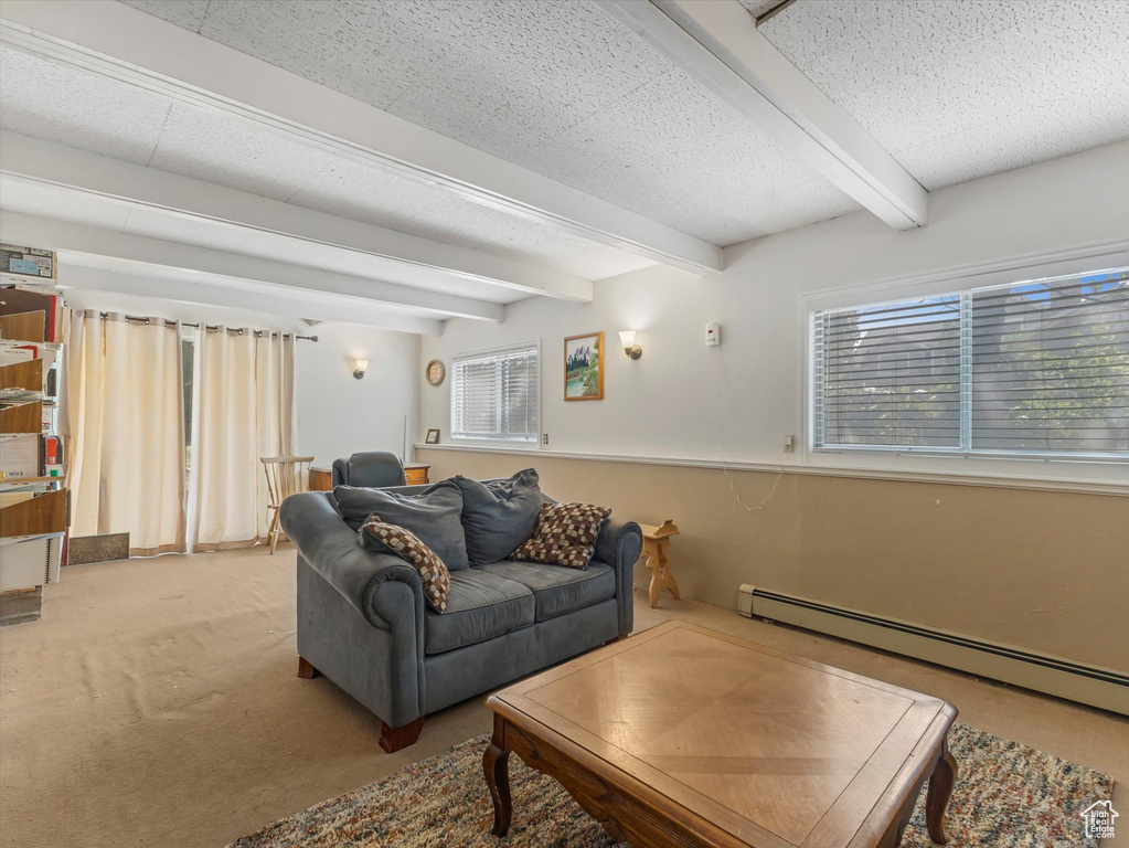 Carpeted living room featuring beam ceiling, healthy amount of natural light, and a baseboard heating unit
