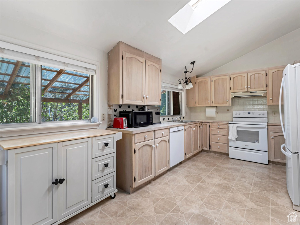 Kitchen featuring white appliances, a skylight, under cabinet range hood, vaulted ceiling, and light brown cabinets