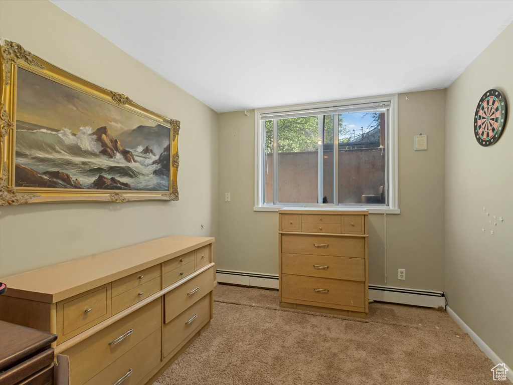 Bedroom with a baseboard heating unit and light colored carpet