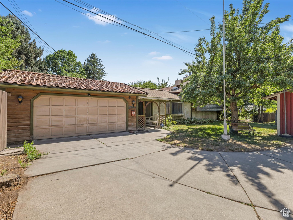 View of front facade with an attached garage, driveway, and a tiled roof
