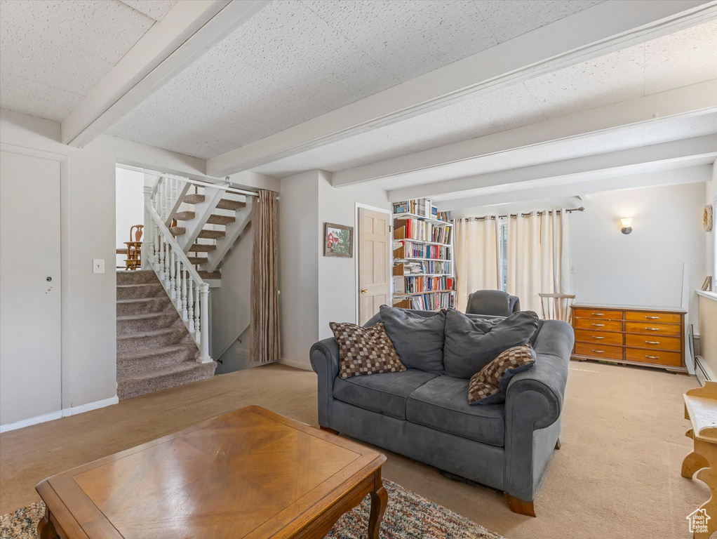 Living room featuring light colored carpet, beam ceiling, and stairs