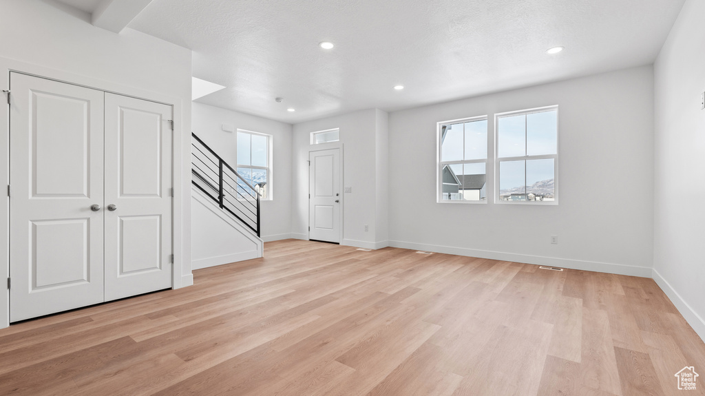 Entrance foyer featuring stairs, plenty of natural light, light wood finished floors, and recessed lighting