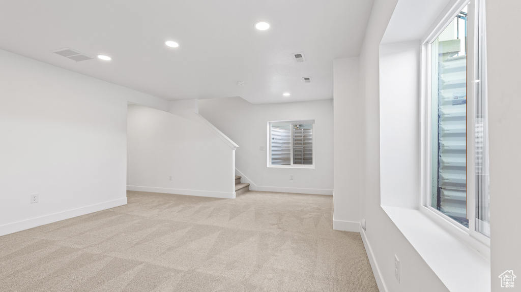 Spare room featuring light colored carpet, recessed lighting, and stairs