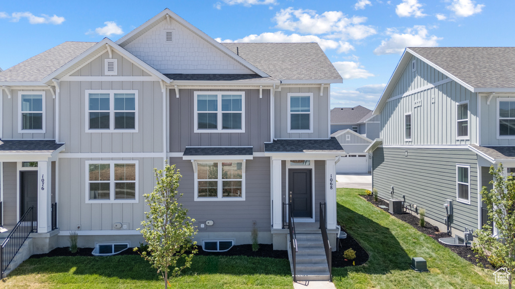 View of front of property featuring board and batten siding, roof with shingles, and a front yard