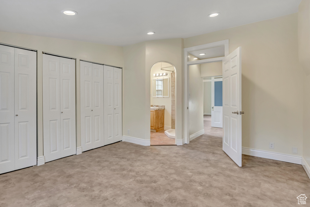 Unfurnished bedroom with two closets, recessed lighting, and ensuite bath