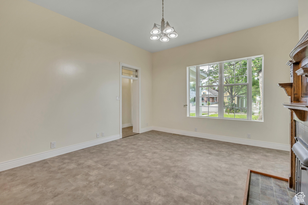 Unfurnished dining area featuring healthy amount of natural light, a tile fireplace, and a chandelier