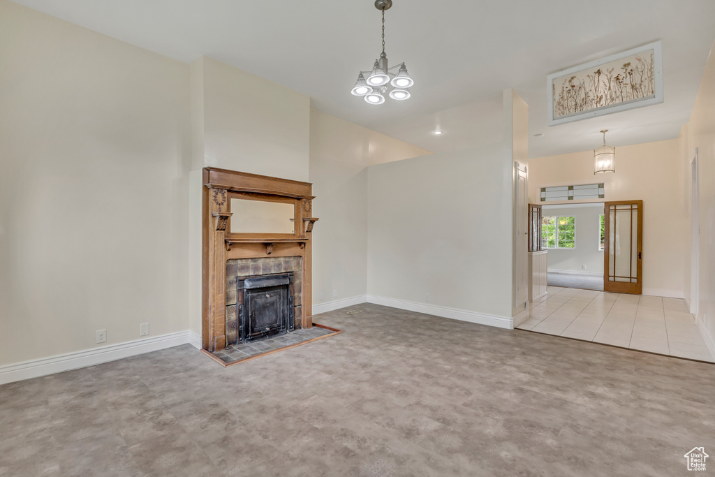 Unfurnished living room with a tiled fireplace and baseboards