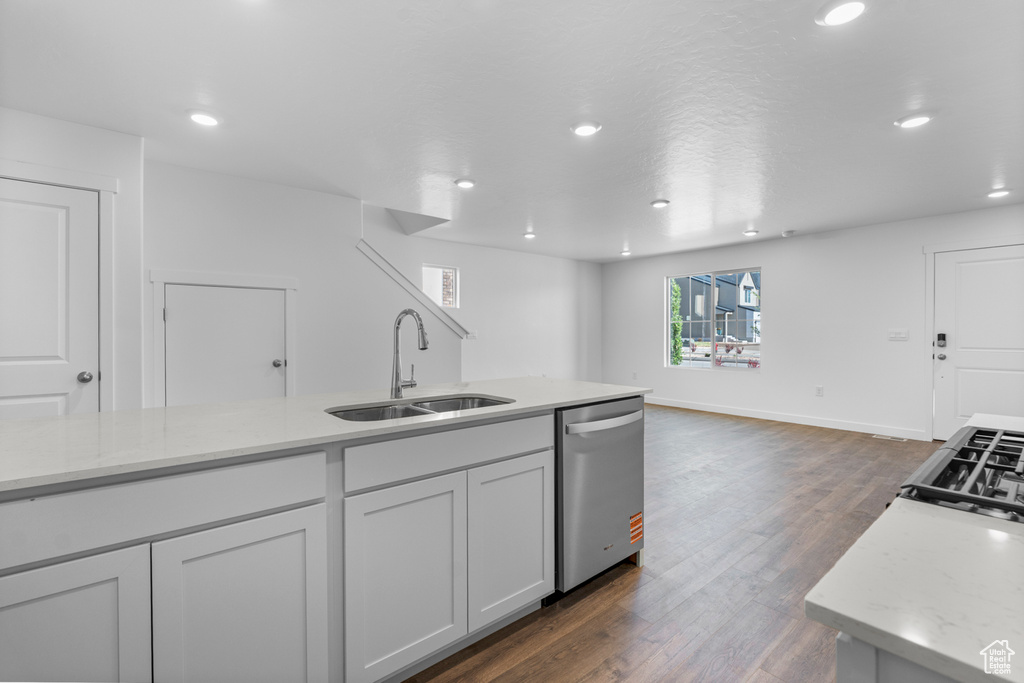 Kitchen featuring stainless steel dishwasher, recessed lighting, dark wood finished floors, open floor plan, and white cabinets