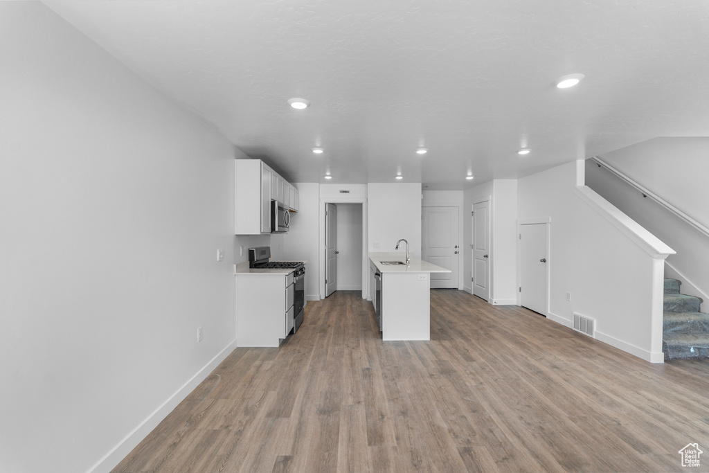 Kitchen featuring stainless steel appliances, light wood-style flooring, light countertops, white cabinetry, and recessed lighting